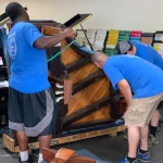 Men Examining a Piano on its side