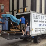 People Moving a large covered object out of a truck