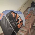 People moving a covered piano on the stairs