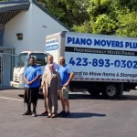 People standing in front of a piano movers plus truck